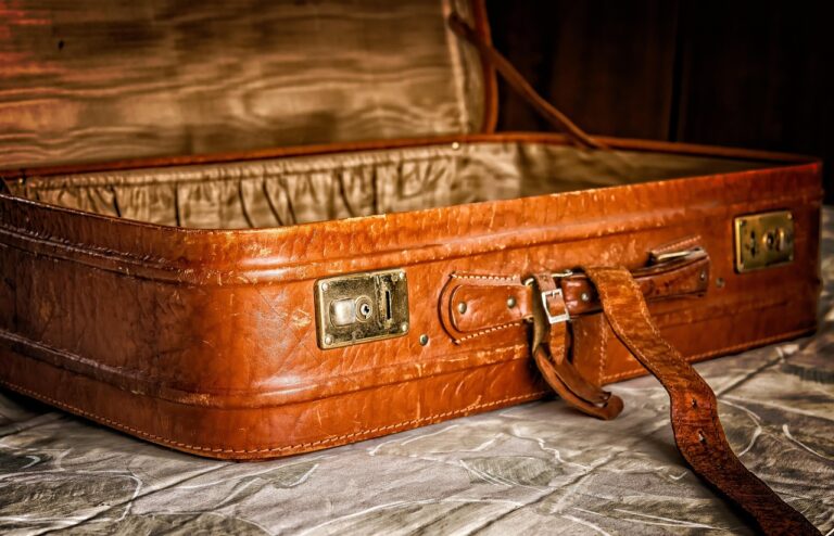 Mala de viagem aberta com roupa, chapéu, máquina fotográfica e artigos de higiene preparados para viajar